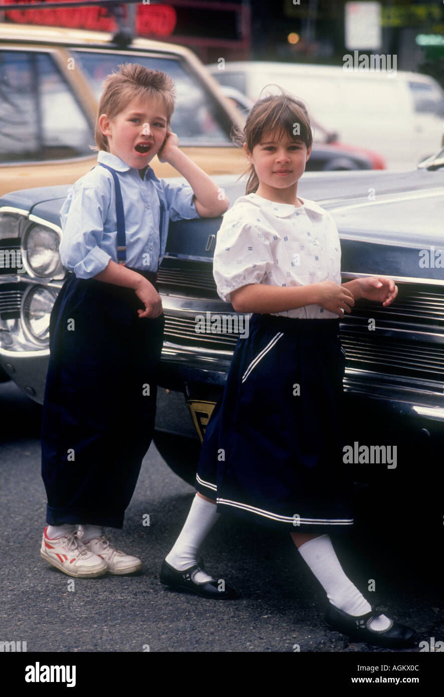 I bambini vestiti di modellazione in una strada di città con americano degli anni cinquanta, Dodge auto Foto Stock