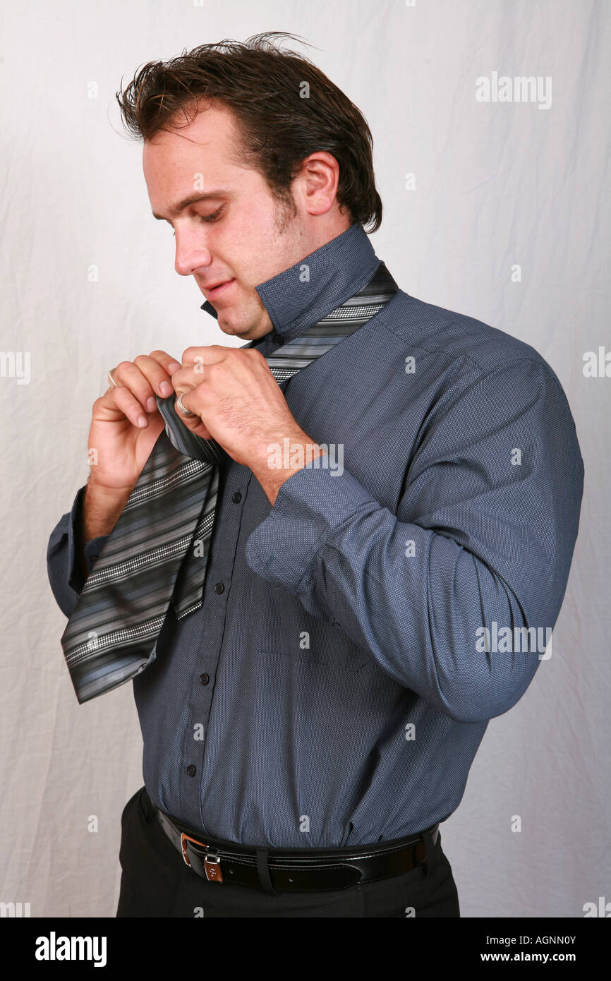 Attraente bel giovane 20s l'uomo maschio cravatte un abito cravatta su un grigio  scuro camicia come egli ottiene vestito con una tuta di lavoro l'ufficio  Foto stock - Alamy