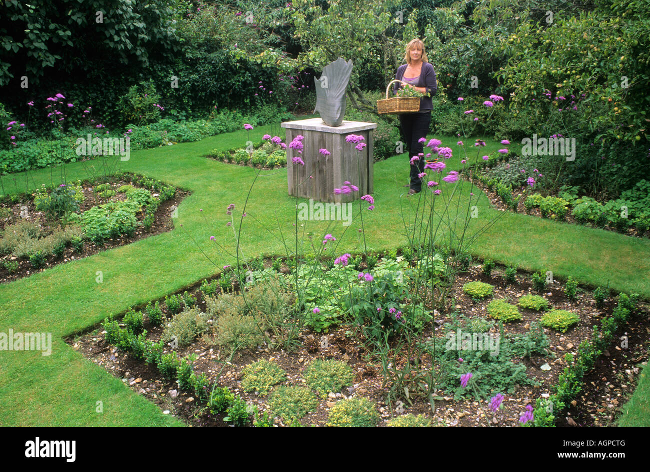 Parterre scultura giardino di erbe aromatiche donna raccolta di erbe nel cestello Foto Stock