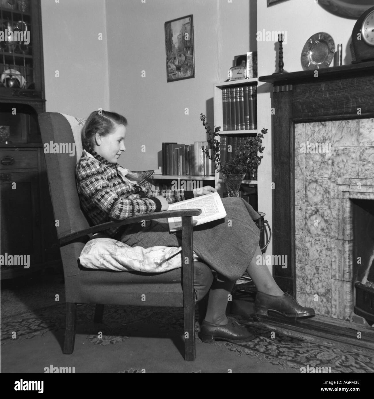 Vecchia famiglia VINTAGE FOTOGRAFIA SNAP SHOT GIOVANE DONNA Libro di lettura da un incendio nel salotto del 1950 circa Foto Stock
