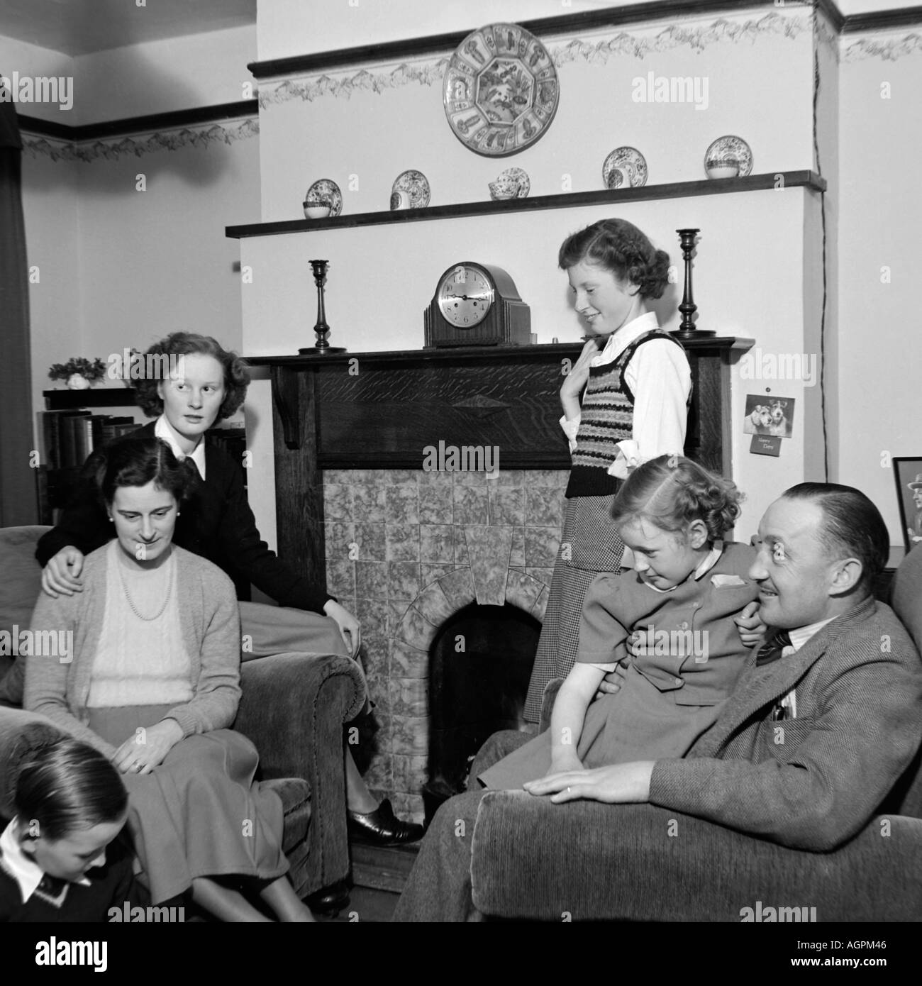 Vecchio VINTAGE IN BIANCO E NERO DI FAMIGLIA fotografia istantanea di madre e padre di quattro figli rilassante nel salotto di casa 1950 Foto Stock