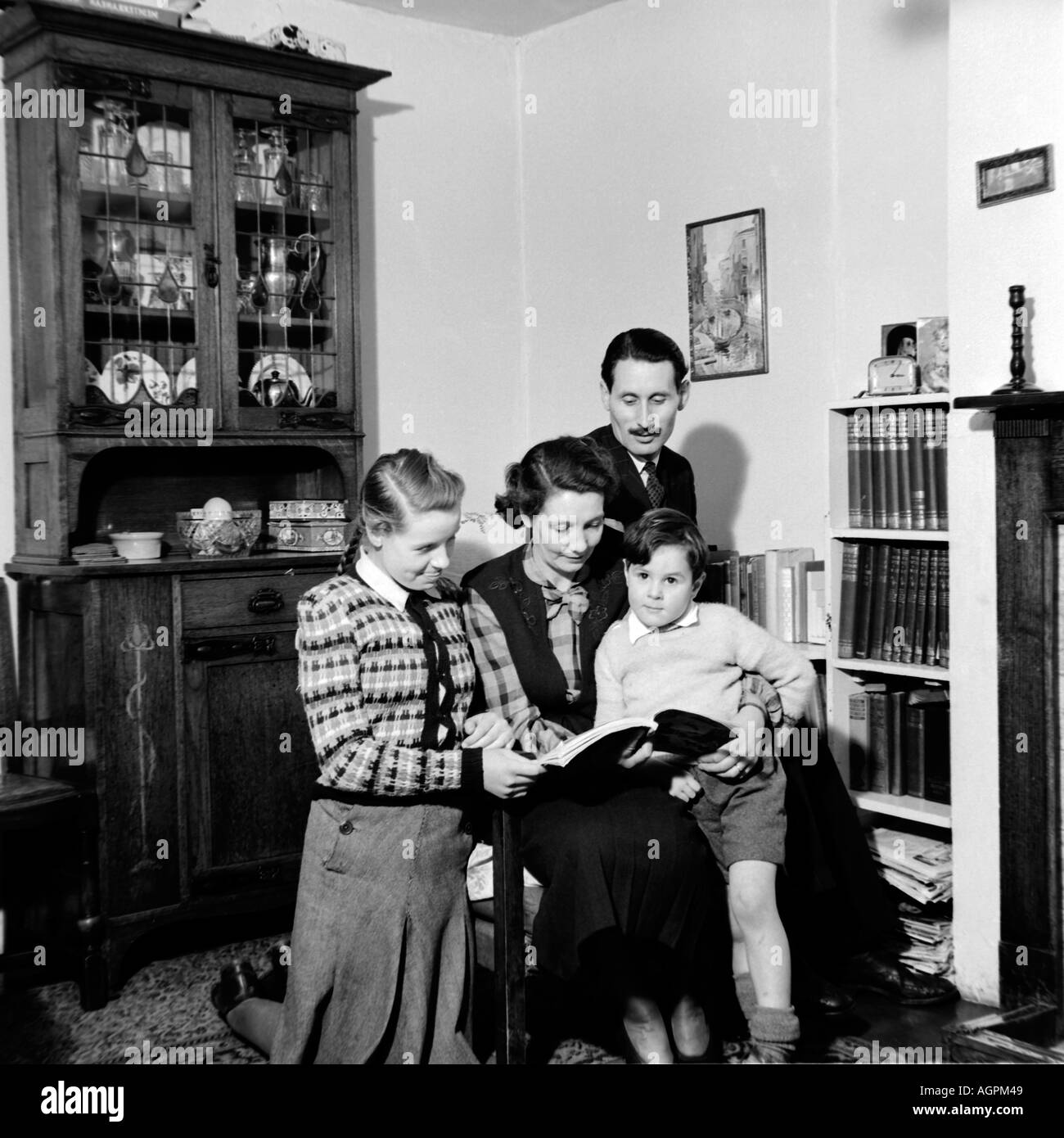 Vecchia famiglia VINTAGE FOTOGRAFIA SNAP SHOT DI GENITORI Libro di lettura per figlio e nostra figlia nel soggiorno del 1950 circa Foto Stock