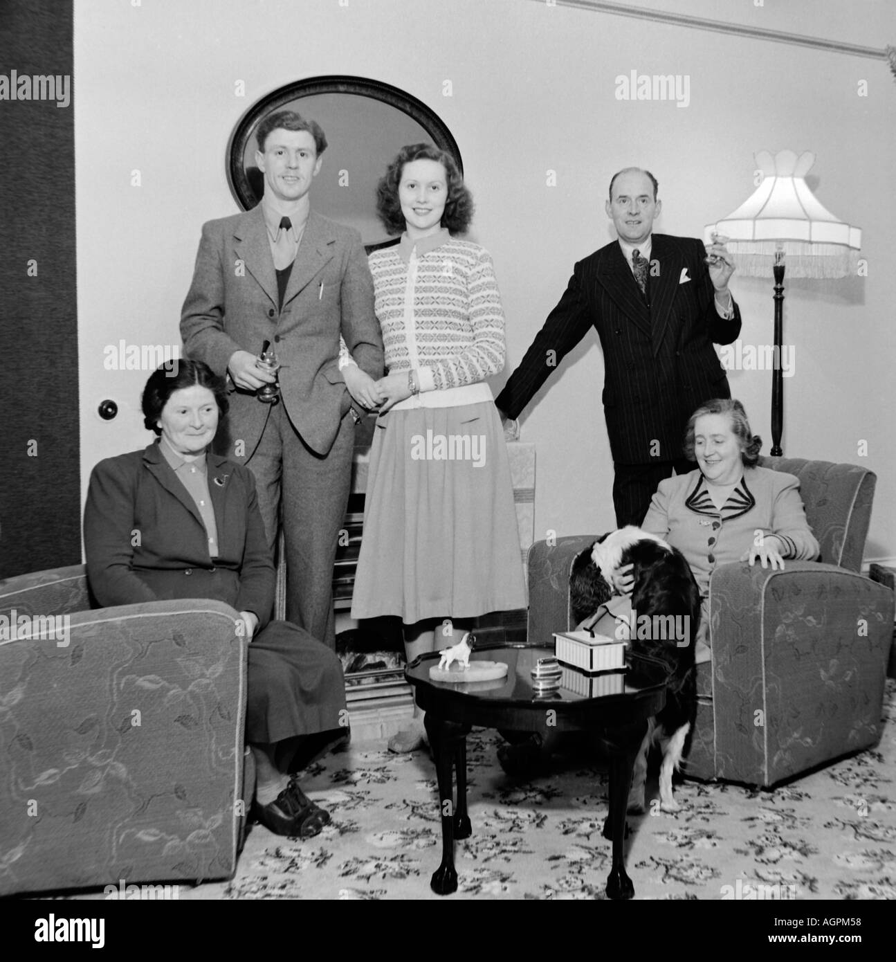 Vecchio VINTAGE IN BIANCO E NERO DI FAMIGLIA fotografia istantanea di gruppo nel salotto del 1950 circa Foto Stock