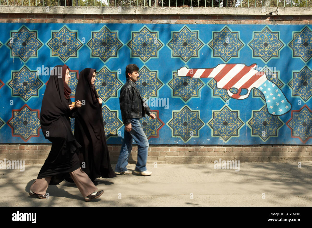 Due donna che indossa chador (islamica Hijab) e un uomo che cammina accanto alle pareti esterne dell'ex-ambasciata degli Stati Uniti a Tehran Foto Stock