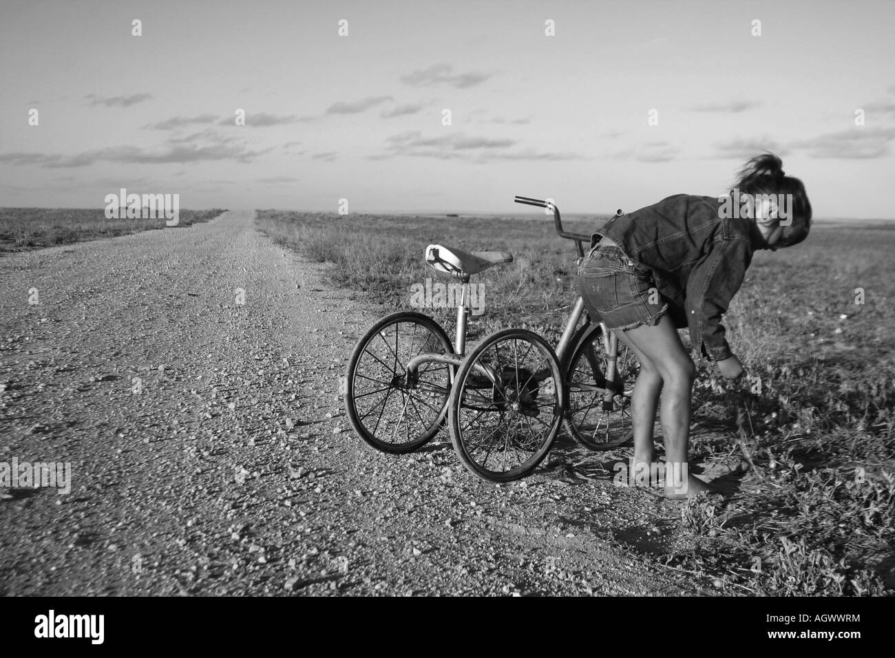 Ragazza giovane in sella bici giù per una strada polverosa Australia Foto Stock