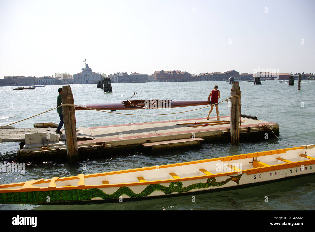 Due uomini sono carring un colorato scull per canottaggio nel Canal Grande di Venezia, Italia Foto Stock