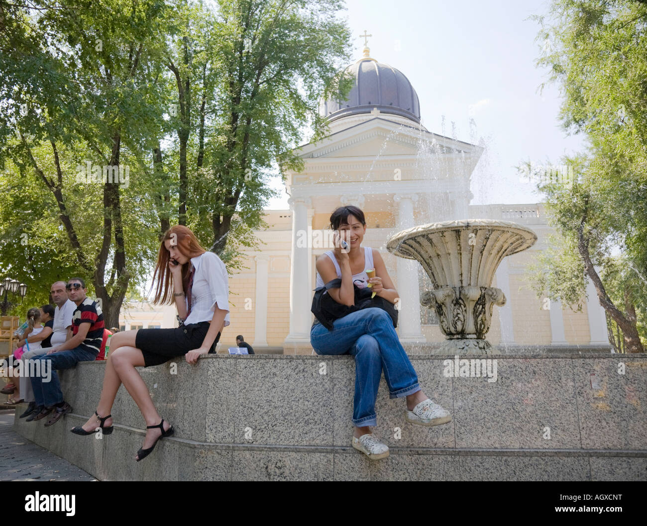 Due giovani donne che utilizzano i loro telefoni cellulari nella parte anteriore del Spaso Preobrazhenskiy cattedrale in Odessa / Ucraina Foto Stock