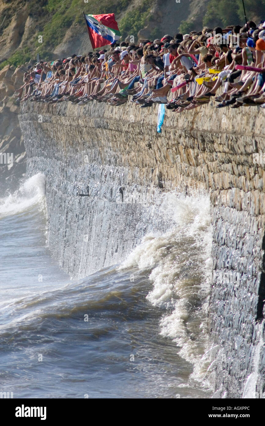 Gli spettatori a guardare traineras regata come mare si blocca sulla parete del mare al di sotto di esse a Puerto Viejo de Algorta Paese Basco in Spagna Foto Stock