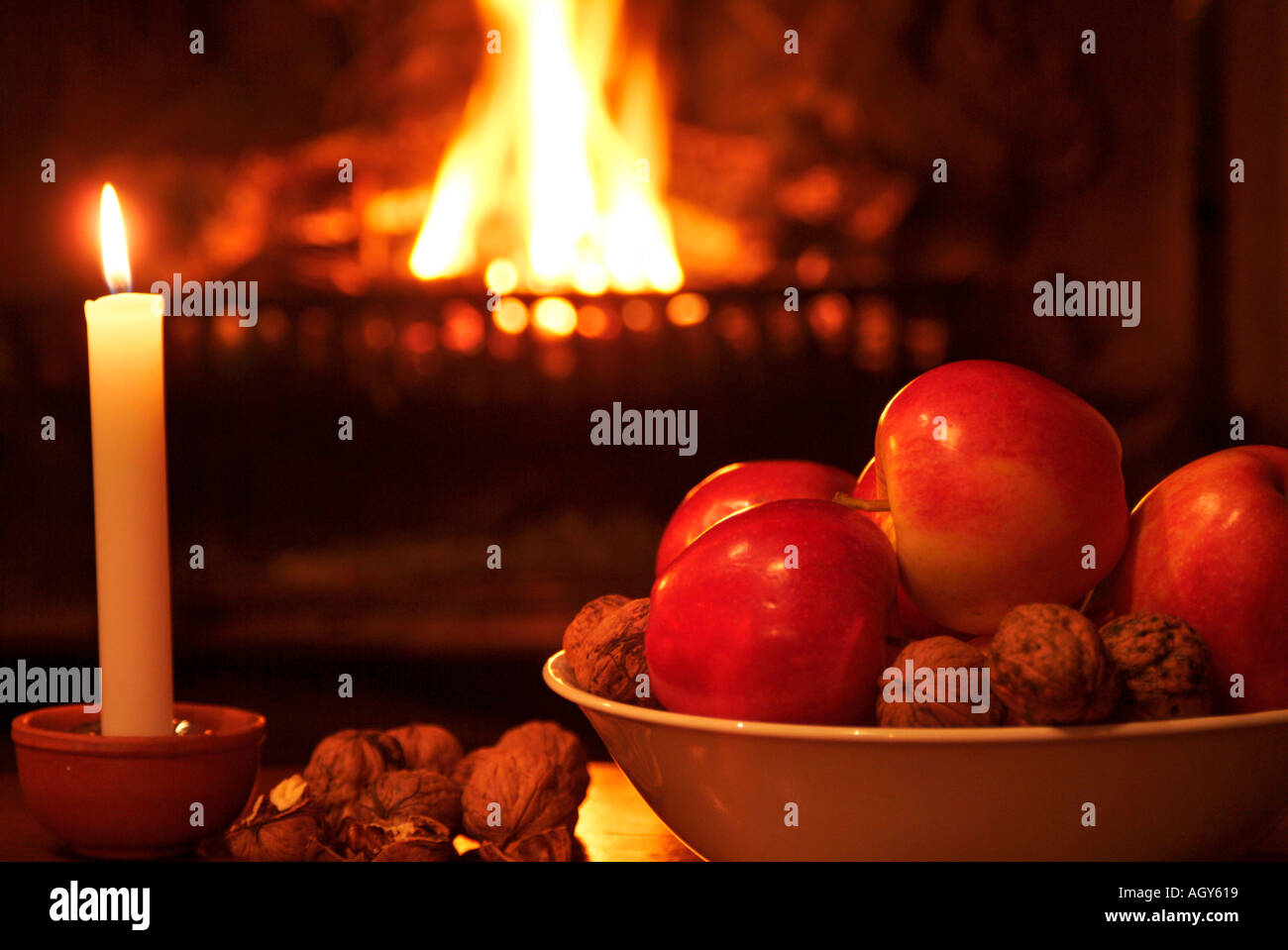 Candela e ciotola con le mele rosse e i dadi nella parte anteriore del fuoco aperto Foto Stock