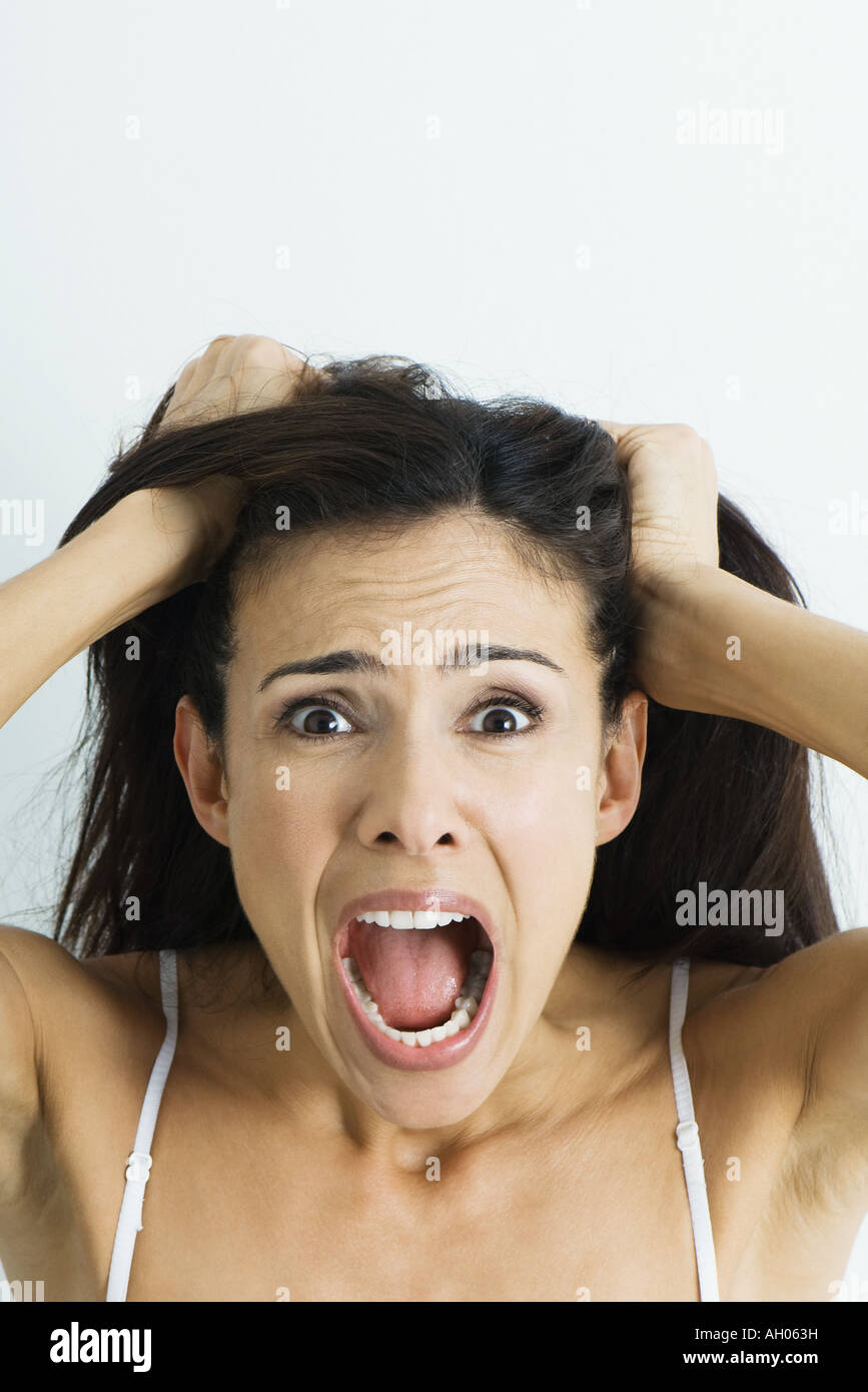 La donna tira i capelli e urlando in telecamera, ritratto Foto Stock