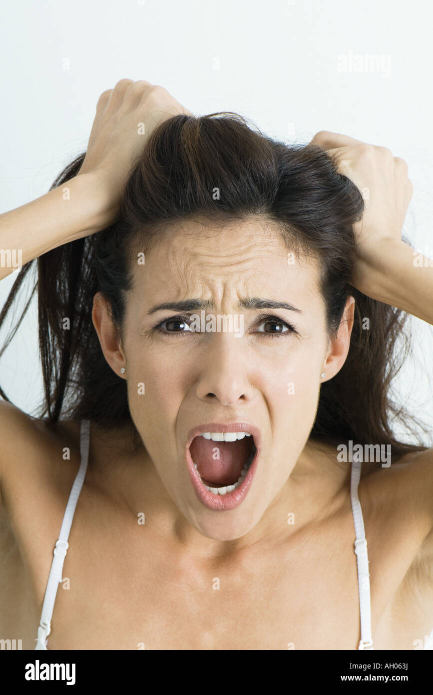 La donna tira i capelli e urlando in telecamera, ritratto Foto Stock