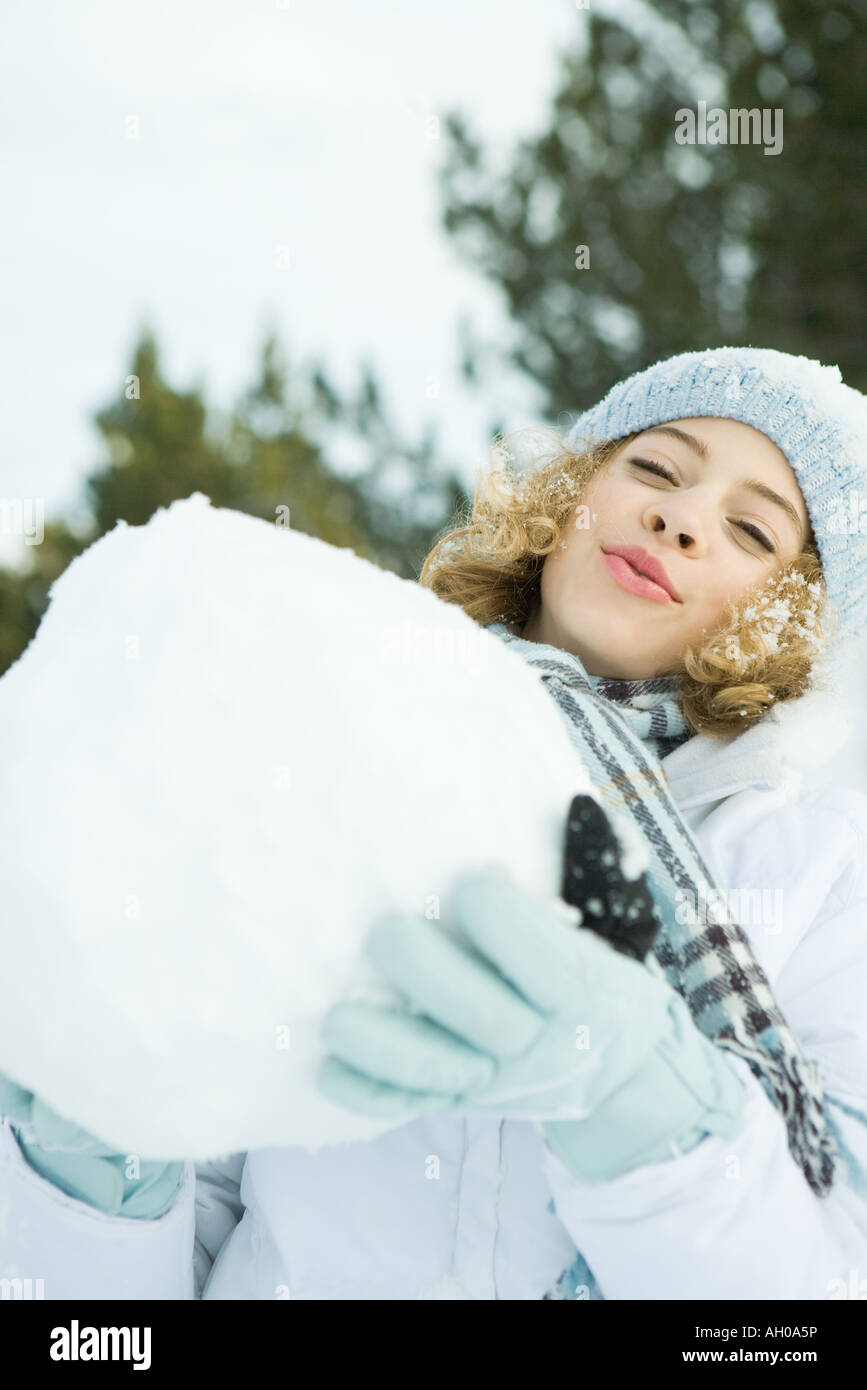 Ragazza adolescente mantenendo la grande palla di neve, sorridente in telecamera, testa indietro Foto Stock