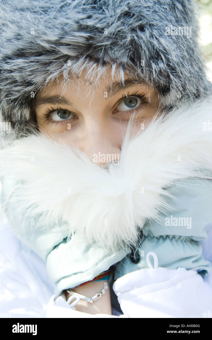 Ragazza adolescente indossando cappello di pelliccia, spingendo il collare di pelliccia sulla bocca, close-up verticale Foto Stock