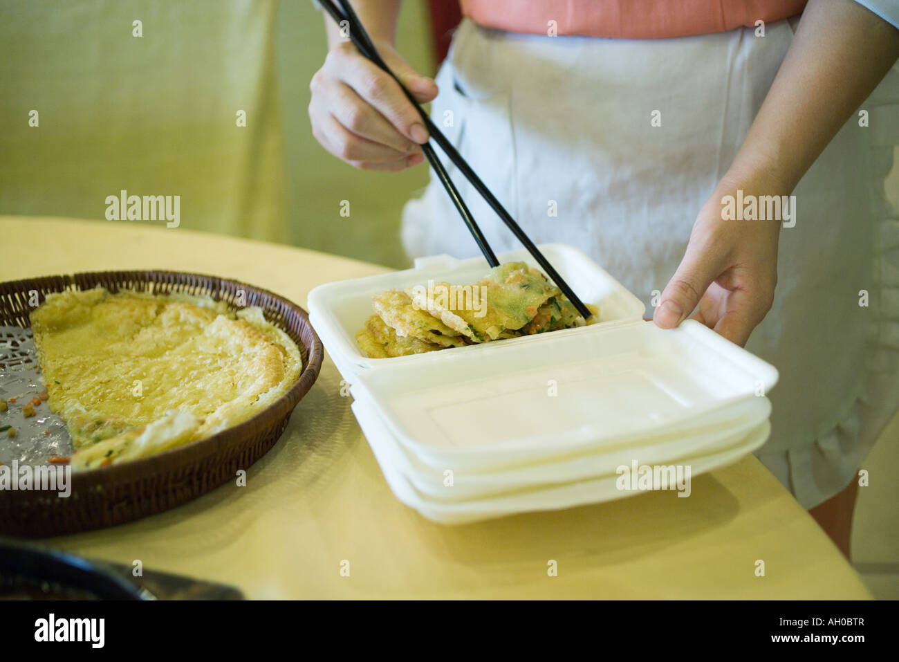 Il servizio di ristorazione personale utilizzando le bacchette per posizionare il cibo nel contenitore in polistirene Foto Stock