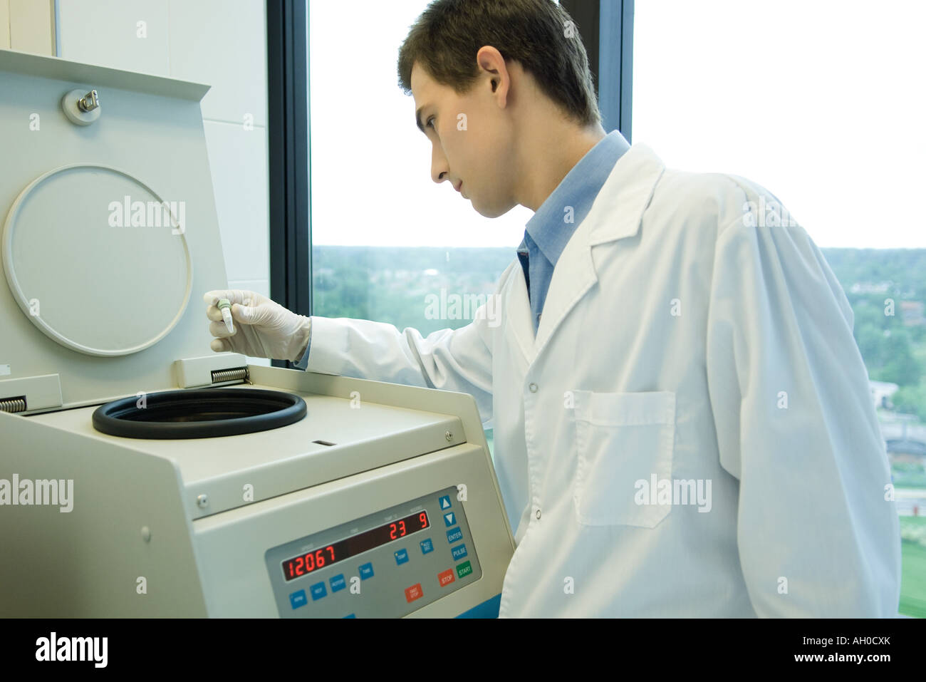 Giovane maschio scienziato utilizzando centrifuga Foto Stock