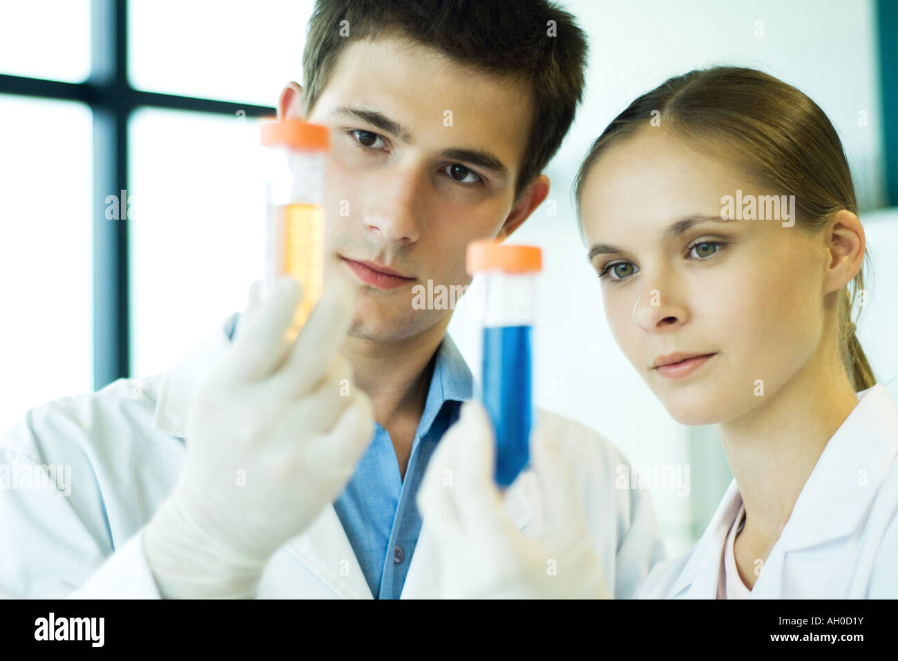 Giovane maschio e femmina dei lavoratori di laboratorio, tenendo su tubi di prova Foto Stock