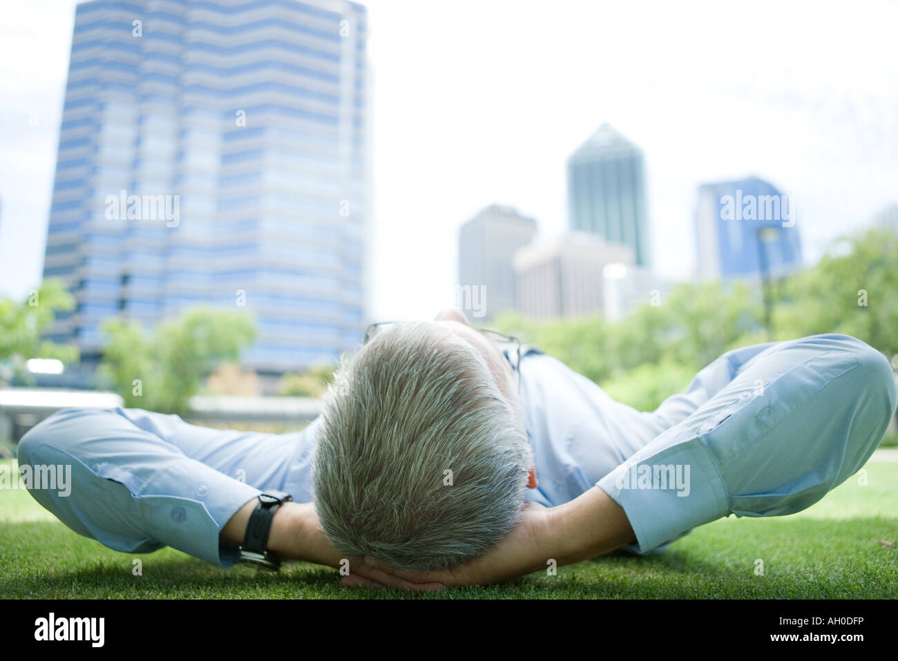 Imprenditore giacente su erba, mani dietro la testa Foto Stock