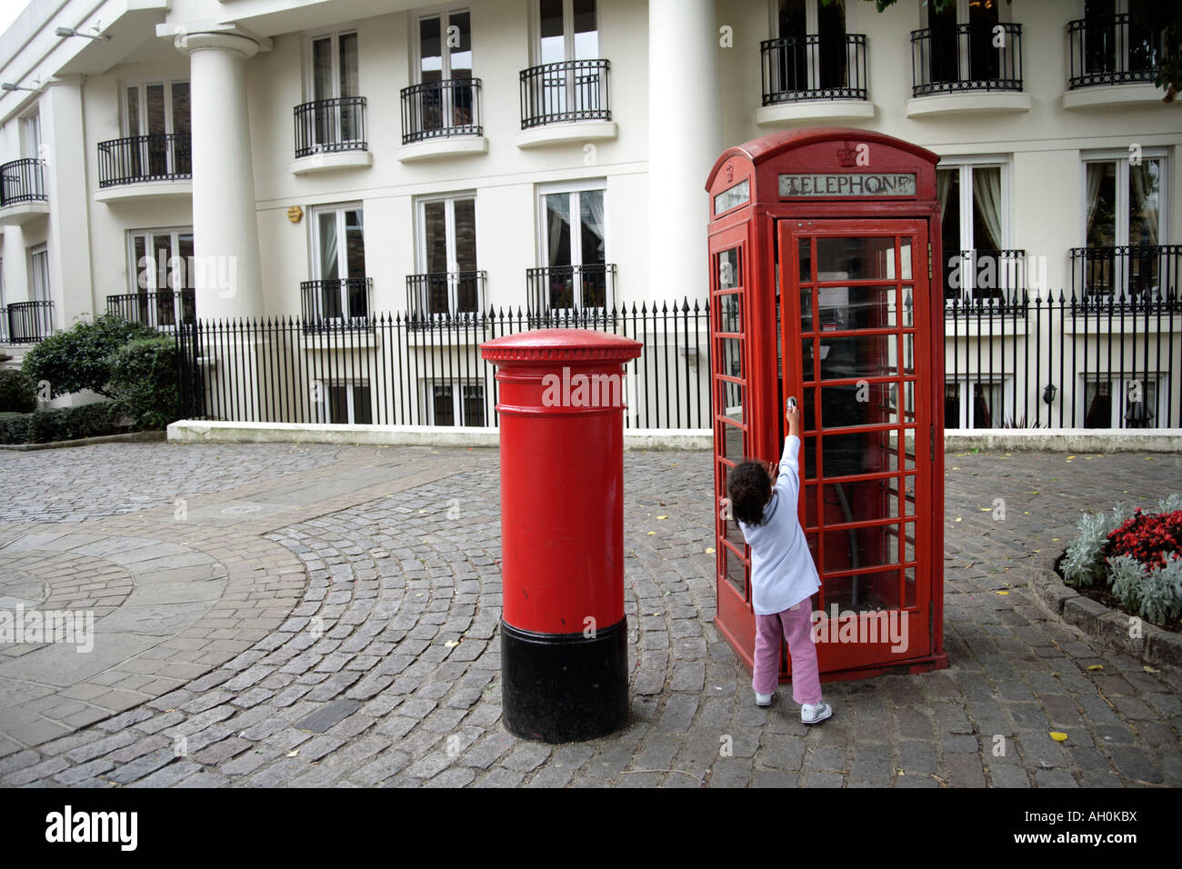 Bambino dal vecchio telefono rosso box e red letter box, St Katharine Docks, London, England, Regno Unito Foto Stock