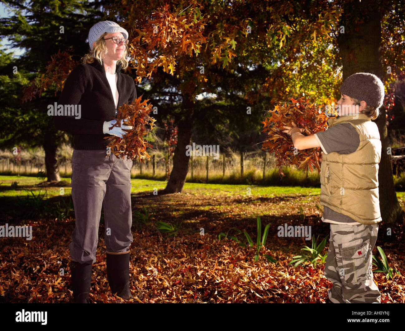 Madre e figlio gettando caduto foglie di autunno a ogni altra in inverno Foto Stock