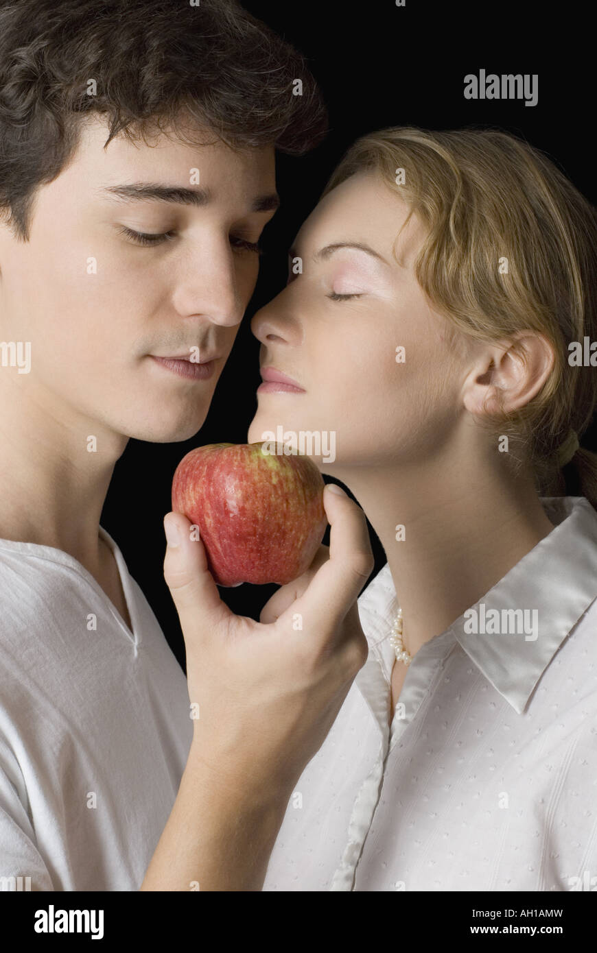 Close-up di un giovane uomo in possesso di un Apple chiuso ad una giovane donna di bocca Foto Stock