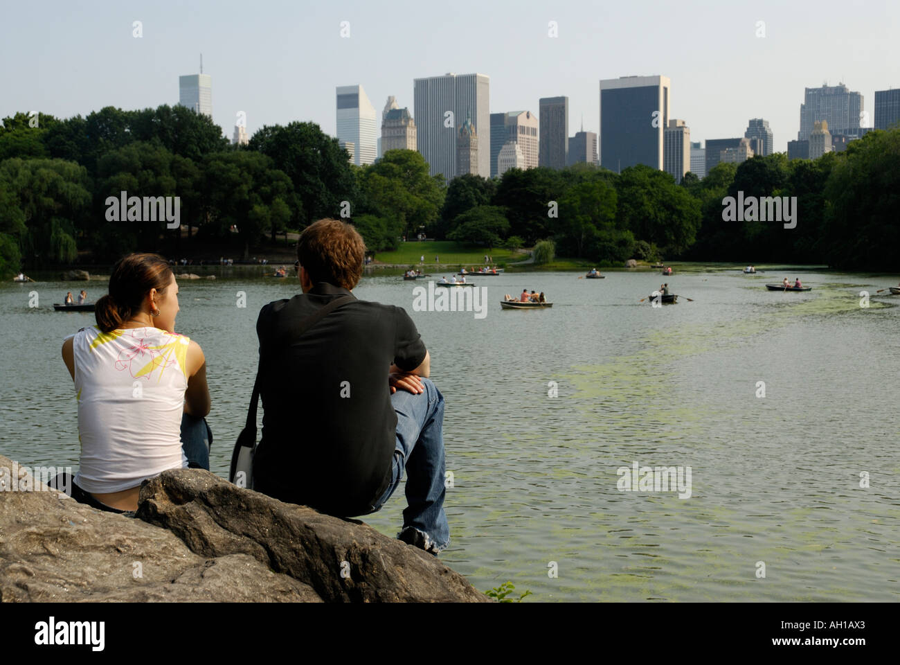 Coppia giovane guardando a Central Park Lake con i barcaioli e New York skyline della città, Manhattan Foto Stock