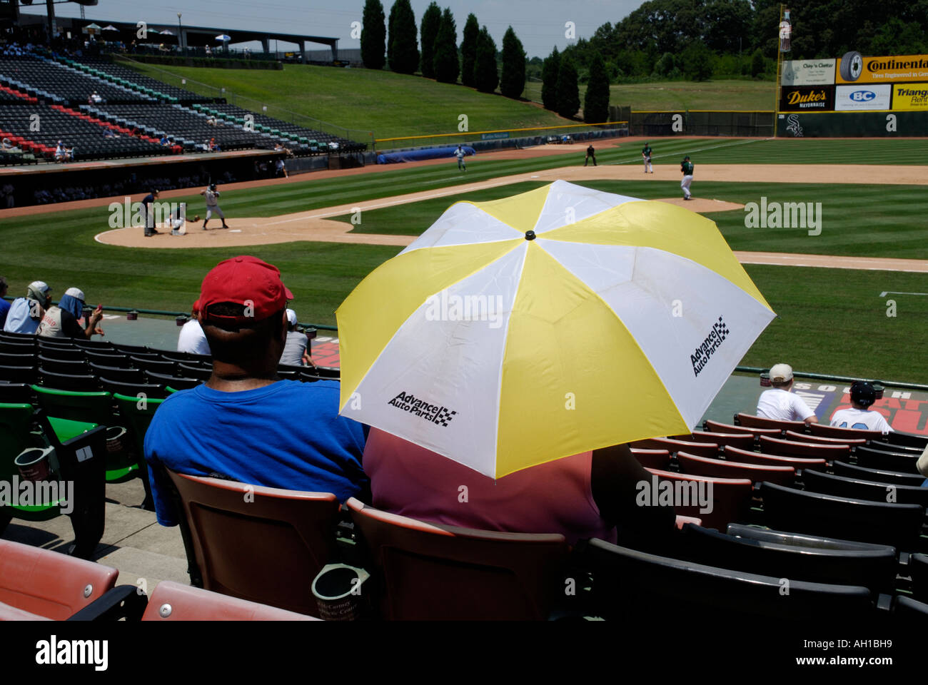 Giovane con colorati ombrello coloratissimo guardando della lega minore di baseball gioco (Charlotte knights), Carolina del Sud Foto Stock