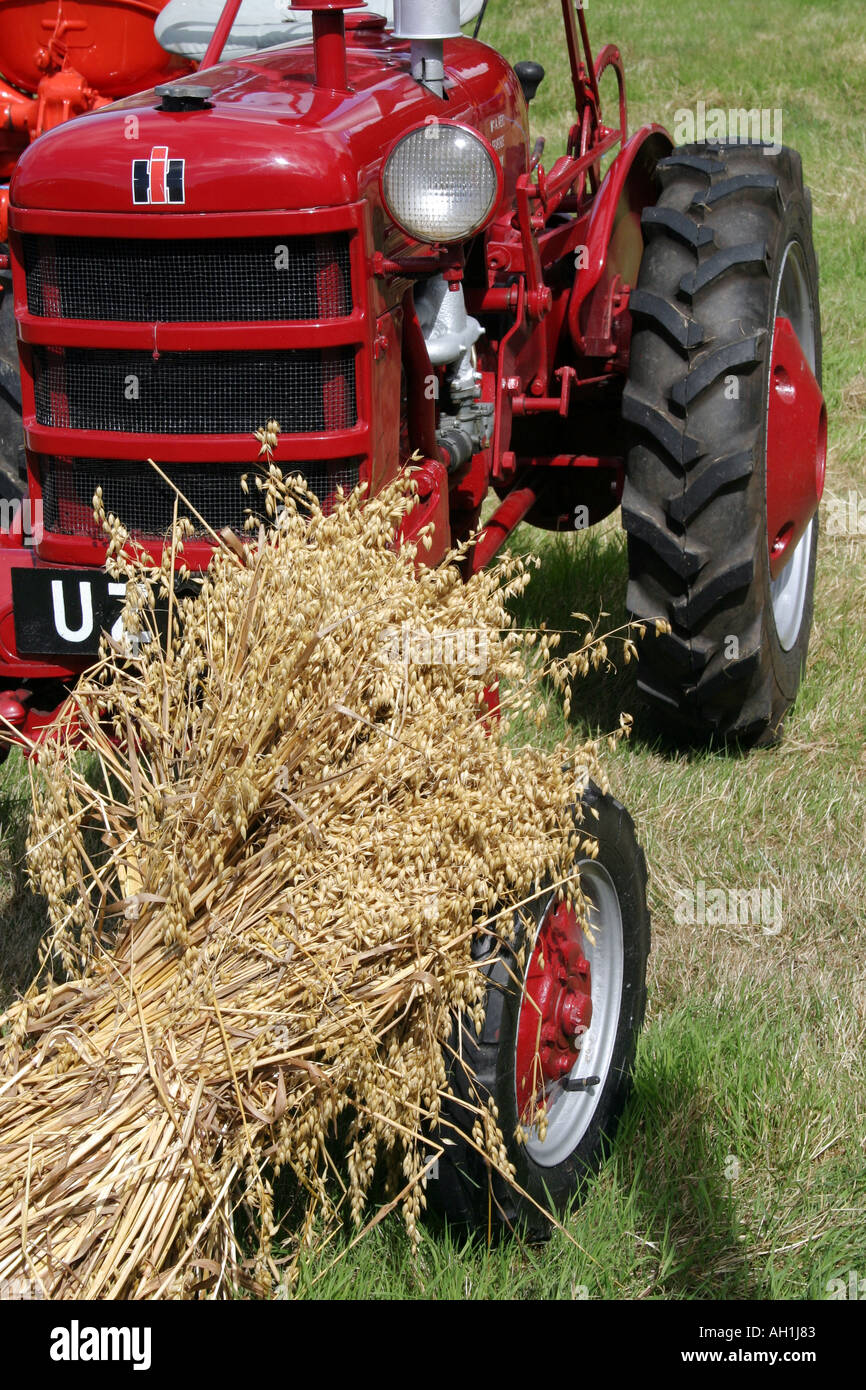 Piccolo trattore rosso e un covone di grano Foto Stock