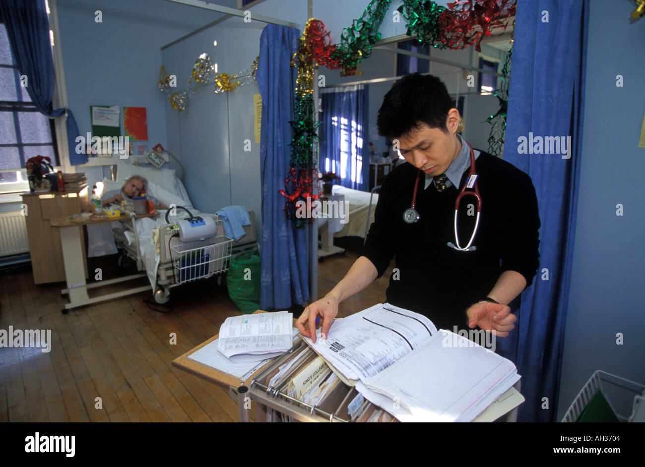 Consulente di esaminare i pazienti anziani note mediche durante il suo giro su un geriatric ward, Kings College Hospital di Londra, Regno Unito. Foto Stock