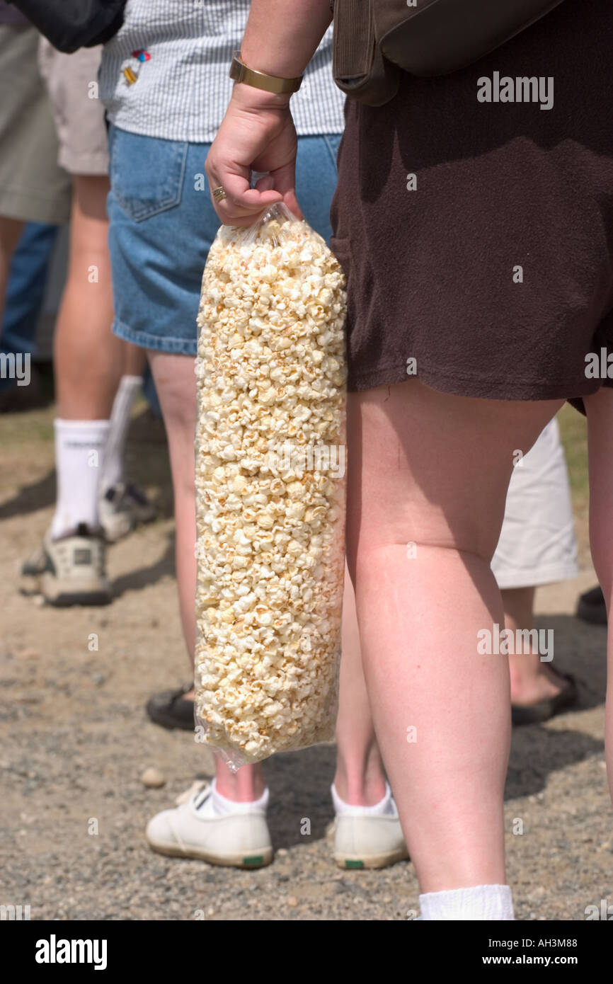 Donna con grandi cosce tenendo un larg sacchetto di pop corn Foto Stock