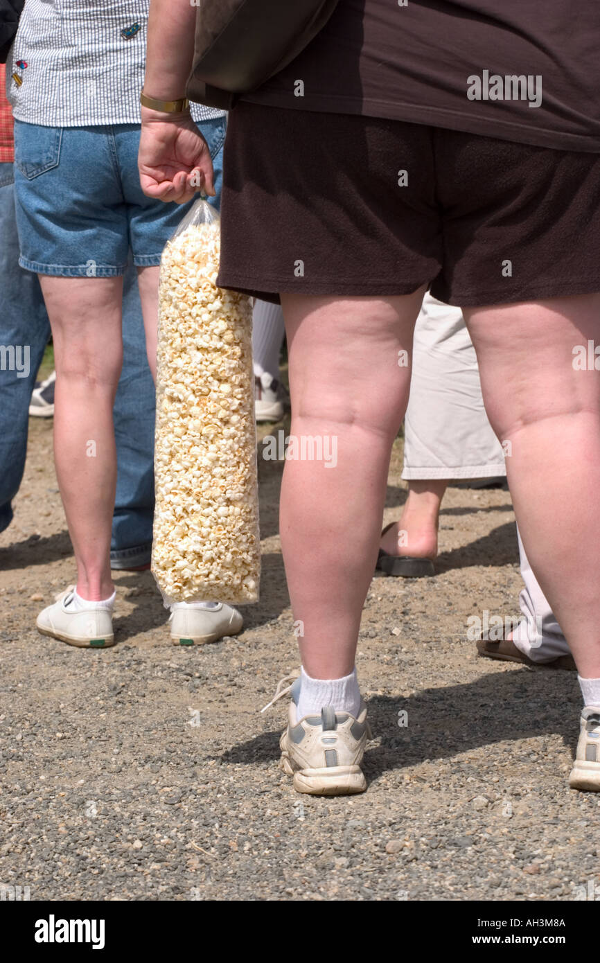 Donna con grandi cosce tenendo un larg sacchetto di pop corn Foto Stock