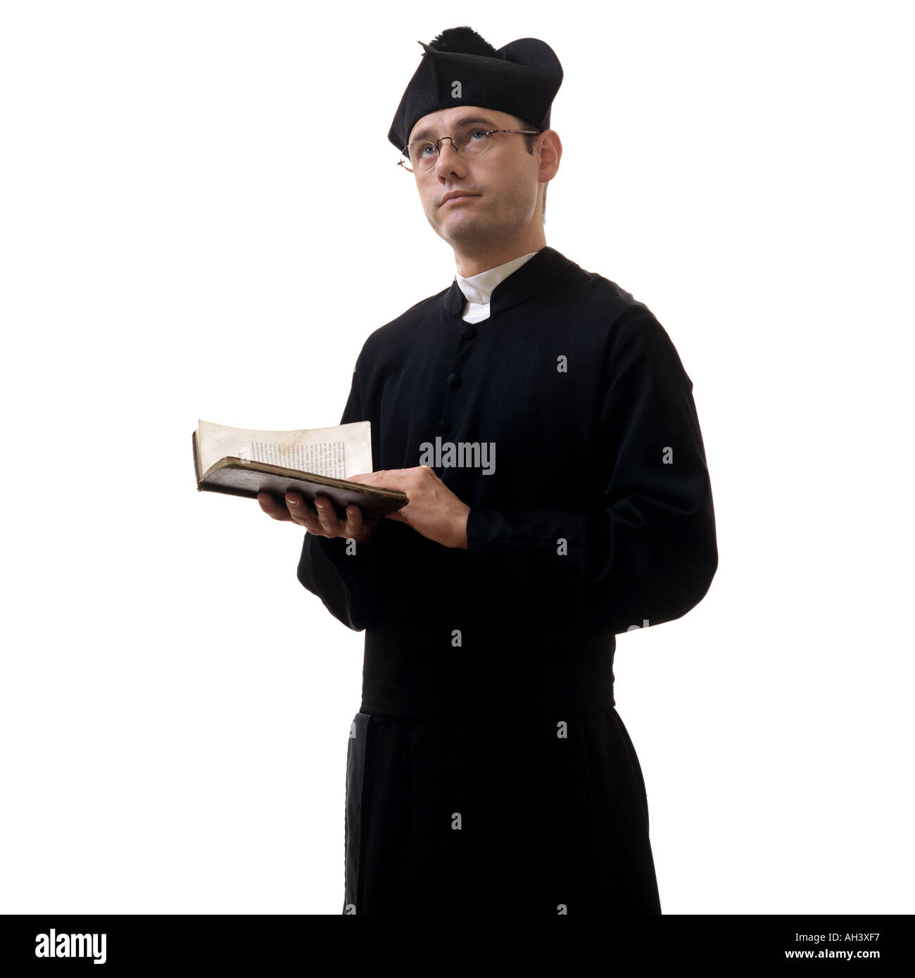 Sacerdote cattolico con un libro di preghiera guardando verso l'alto Foto Stock