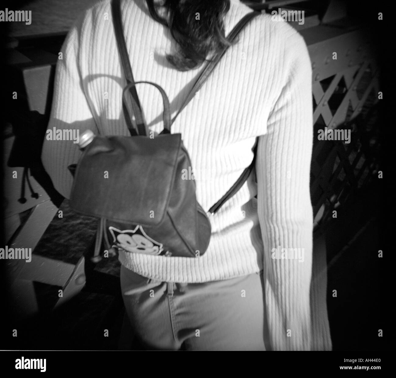 Una donna in bianco lasciato lungo il ponticello a piedi con un piccolo zaino square raccolto in bianco e nero Foto Stock