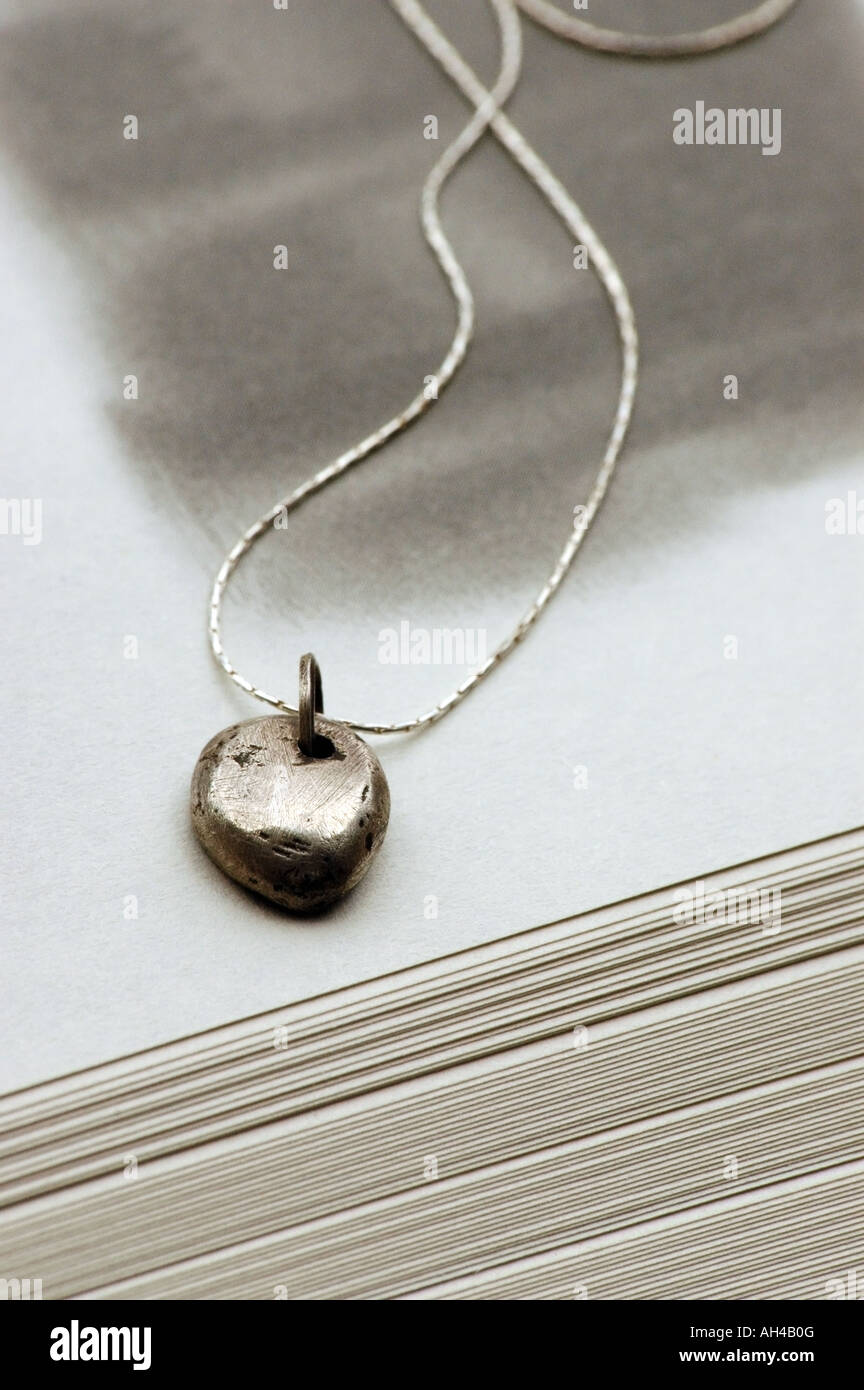 Un argento nugget collana prevista su un libro aperto. Foto Stock
