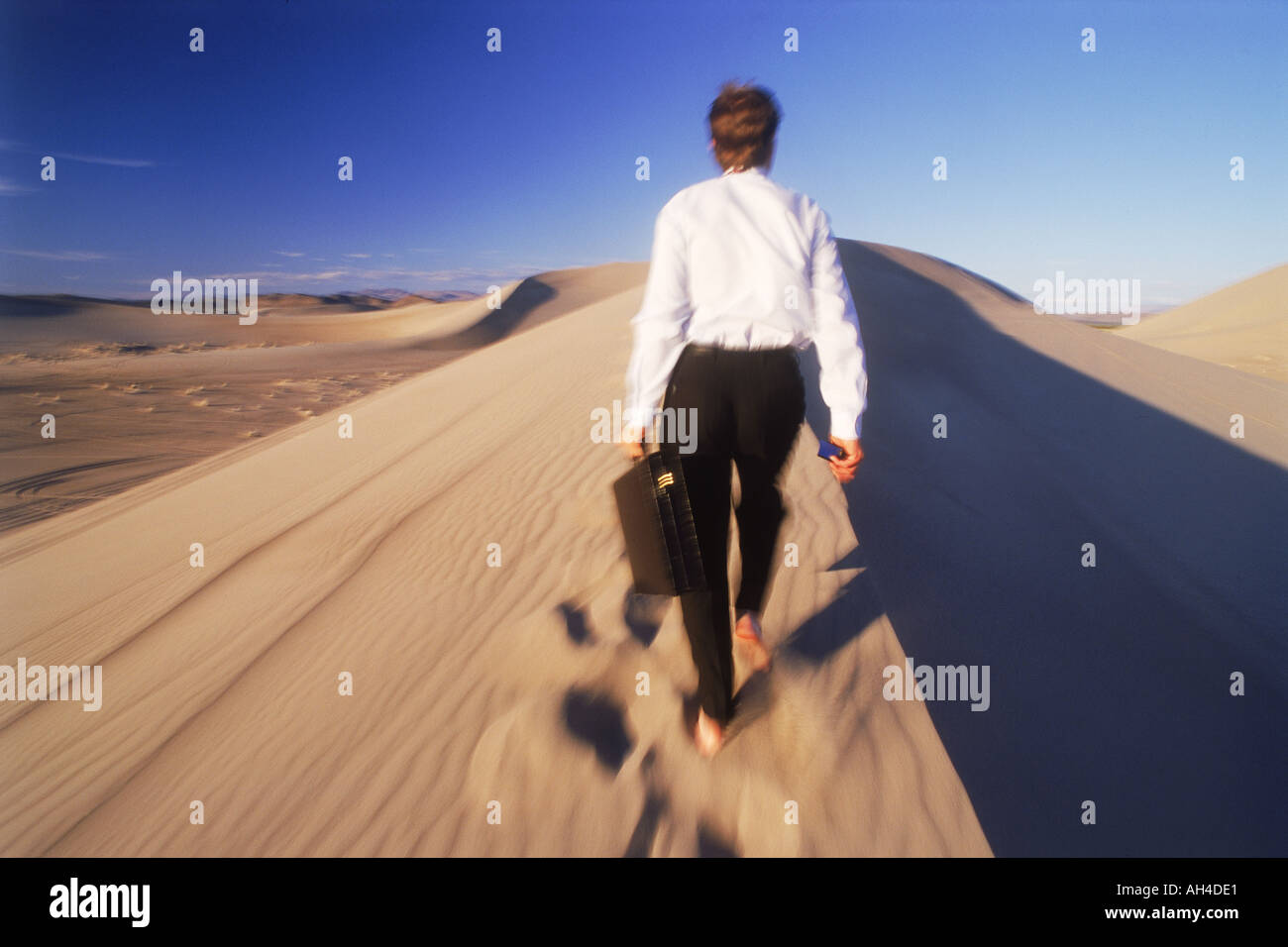 Imprenditore con valigetta camminando sulle dune di sabbia in Nevada Foto Stock