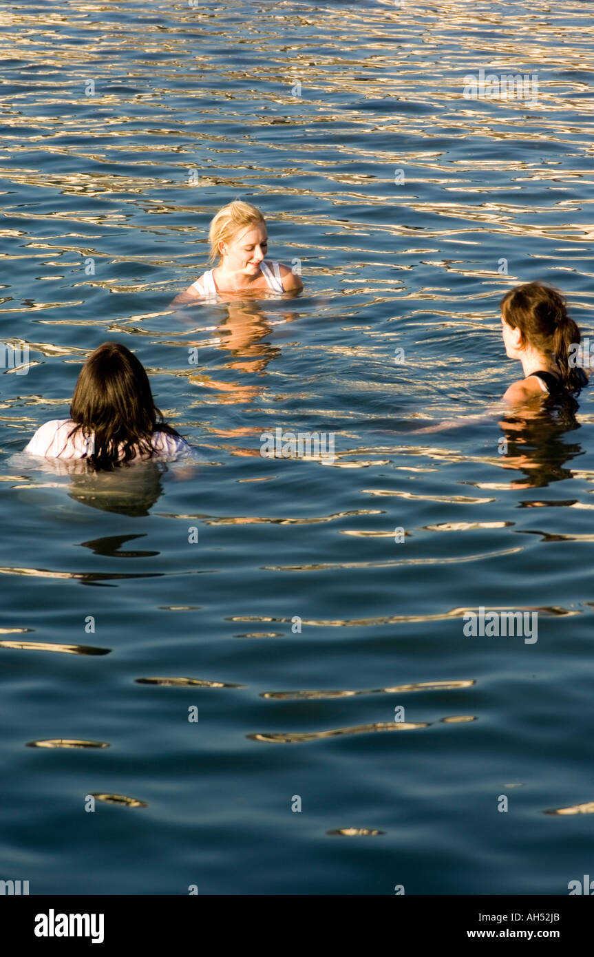 Felice di tre giovani donne fino alle loro spalle in mare al largo della costa di Aberystwyth Cardigan Bay ceredigion estate sole pomeridiano Foto Stock