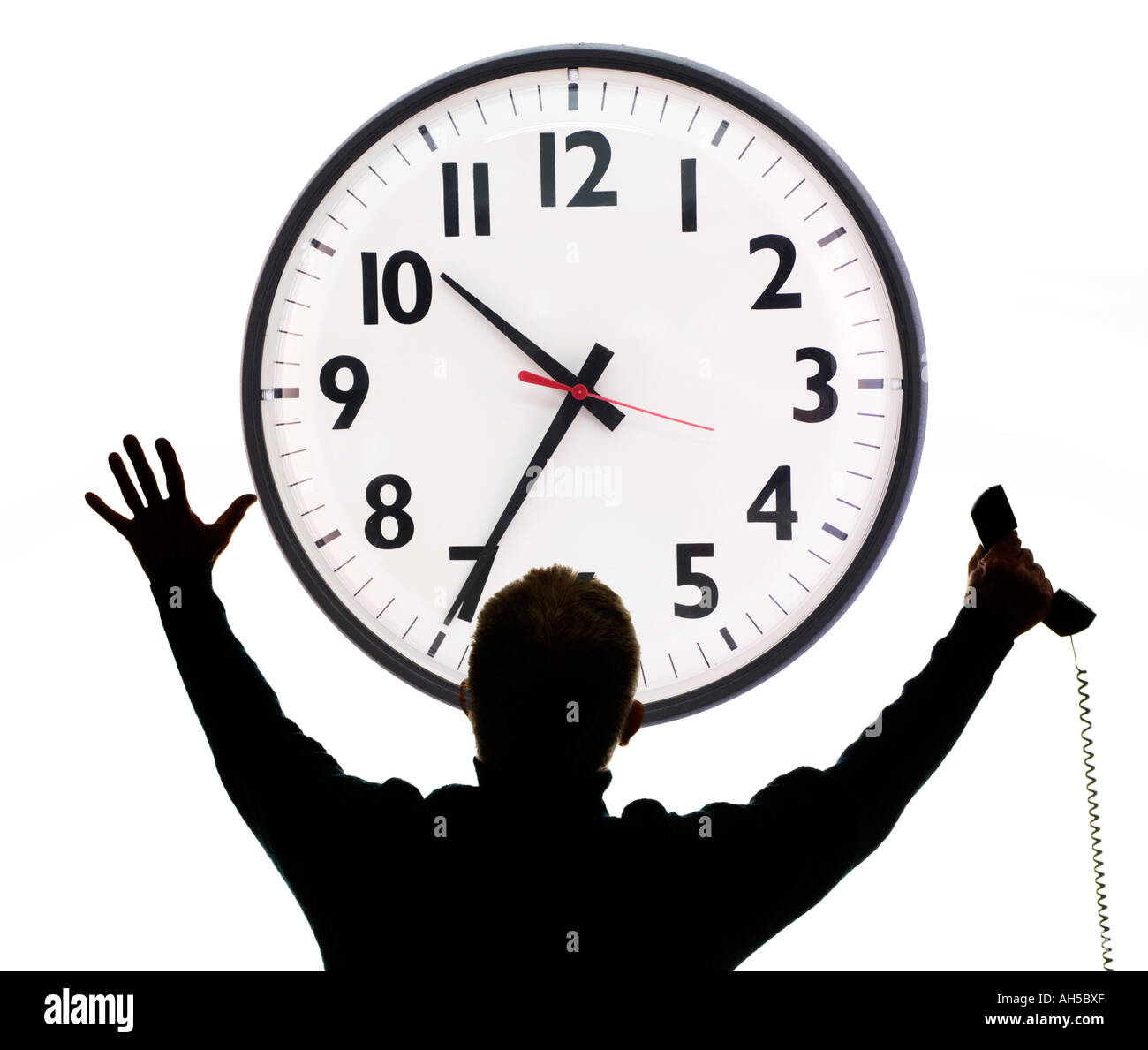 Silhouette di un imprenditore con telefono e braccia tese con sottofondo di ufficio enorme orologio da parete Foto Stock