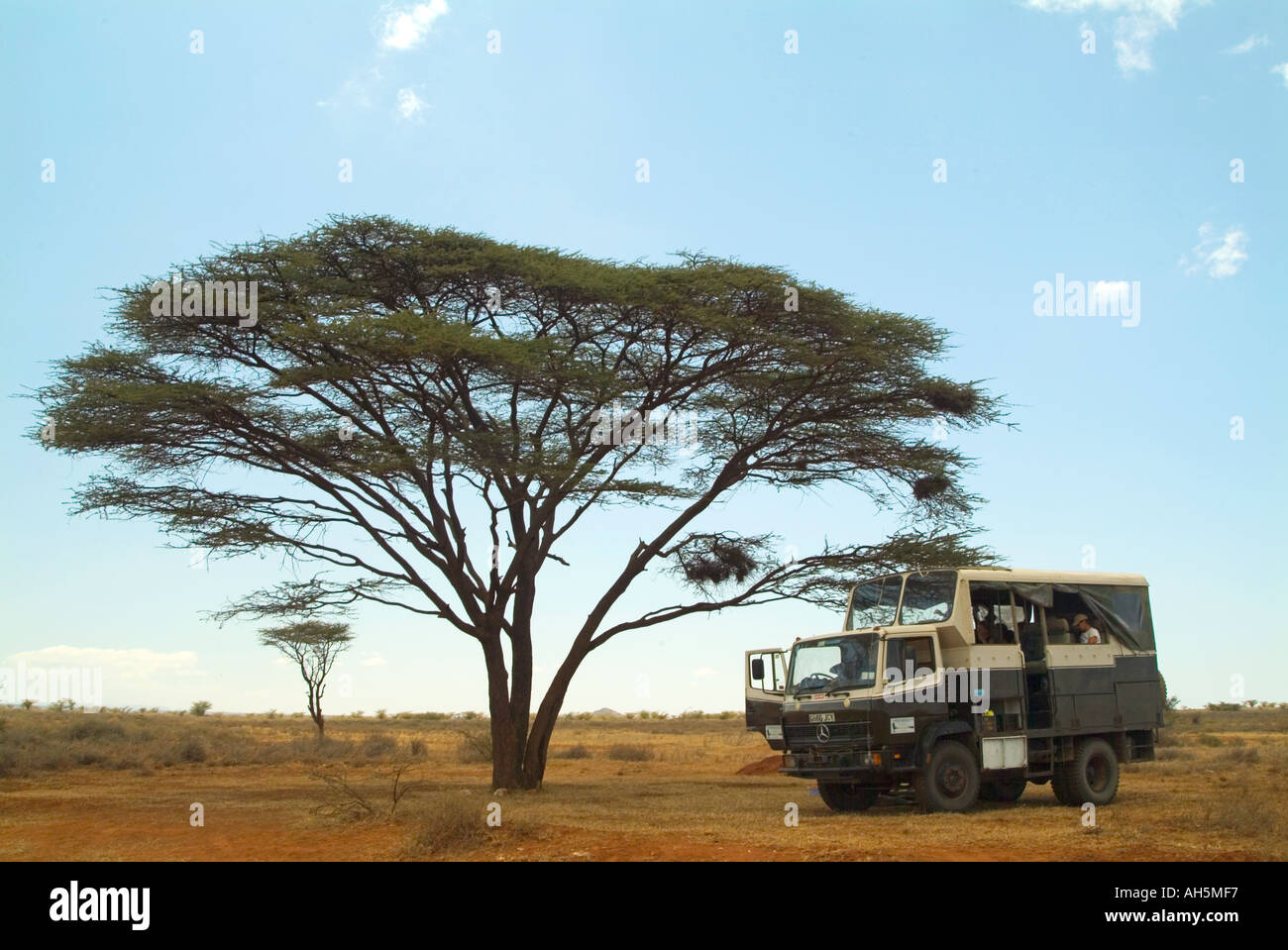 Un overland viaggiatori parchi del carrello sotto un albero nel calore del Kenya. South Horr, nel nord del Kenya, Africa orientale. Foto Stock