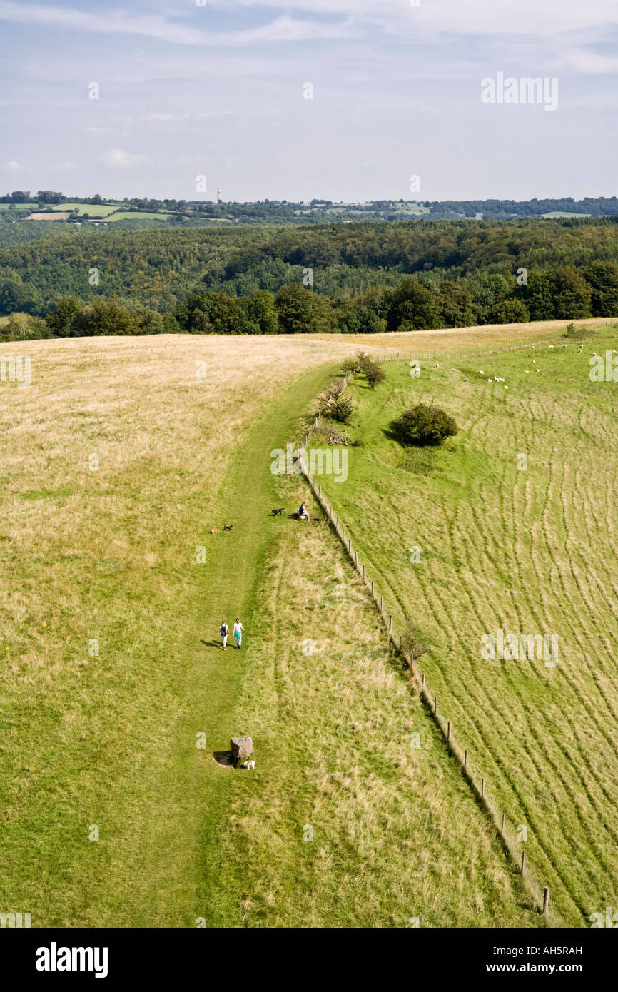 Walkers sul Cotswold Way passando il piede del monumento Tyndales al di sopra del villaggio Costwold di North Nibley, Gloucestershire Foto Stock