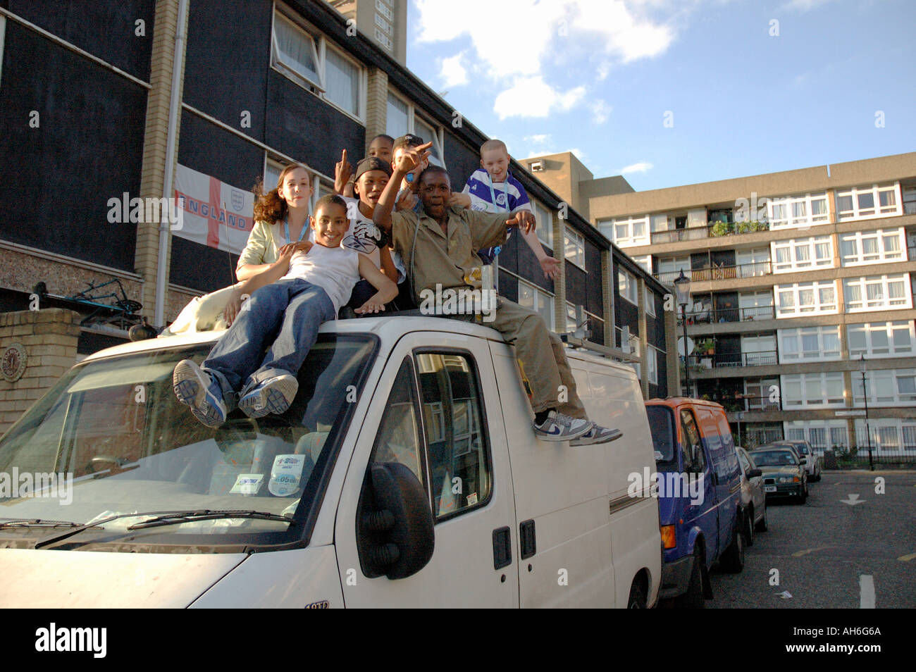 Gruppo vivace dei bambini di arrampicata e saltare sul furgone parcheggiato sul loro alloggiamento estate in Kensal Green West London. Foto Stock