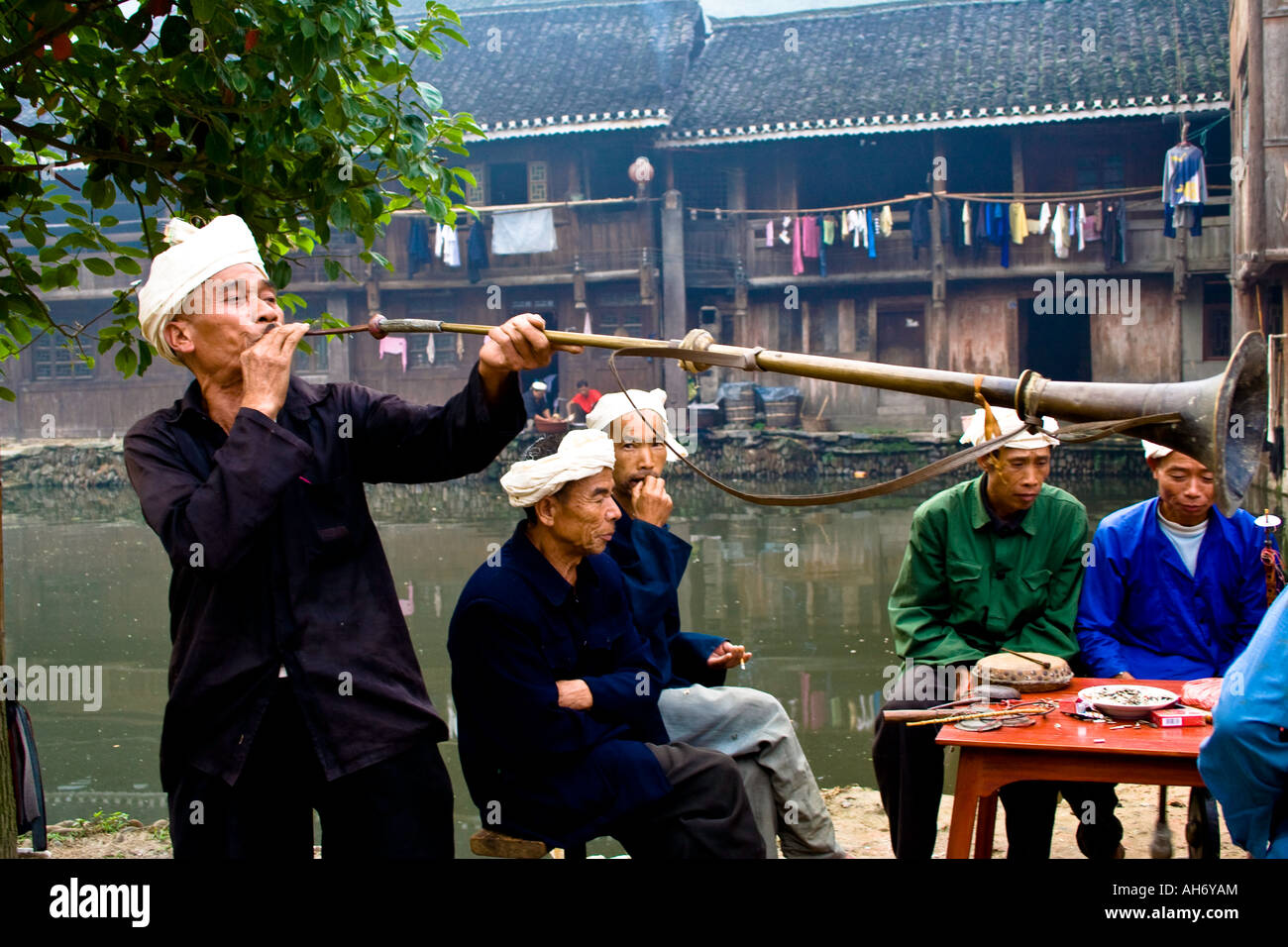L'uomo Soffia lungo il corno di ottone per Dong cinese minoranza etnica funerale Zhaoxing Cina Foto Stock