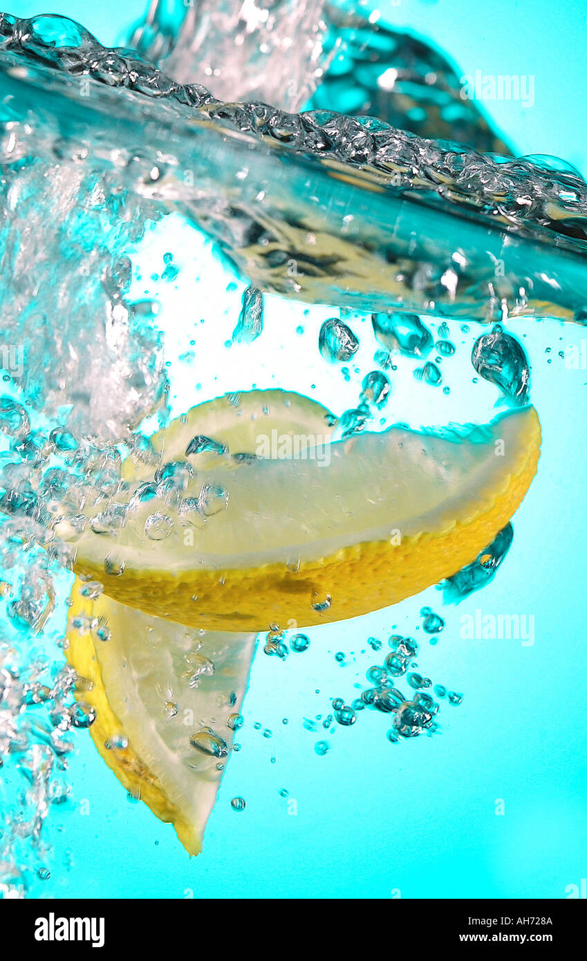 Fette di limone cadere nel bere Foto Stock