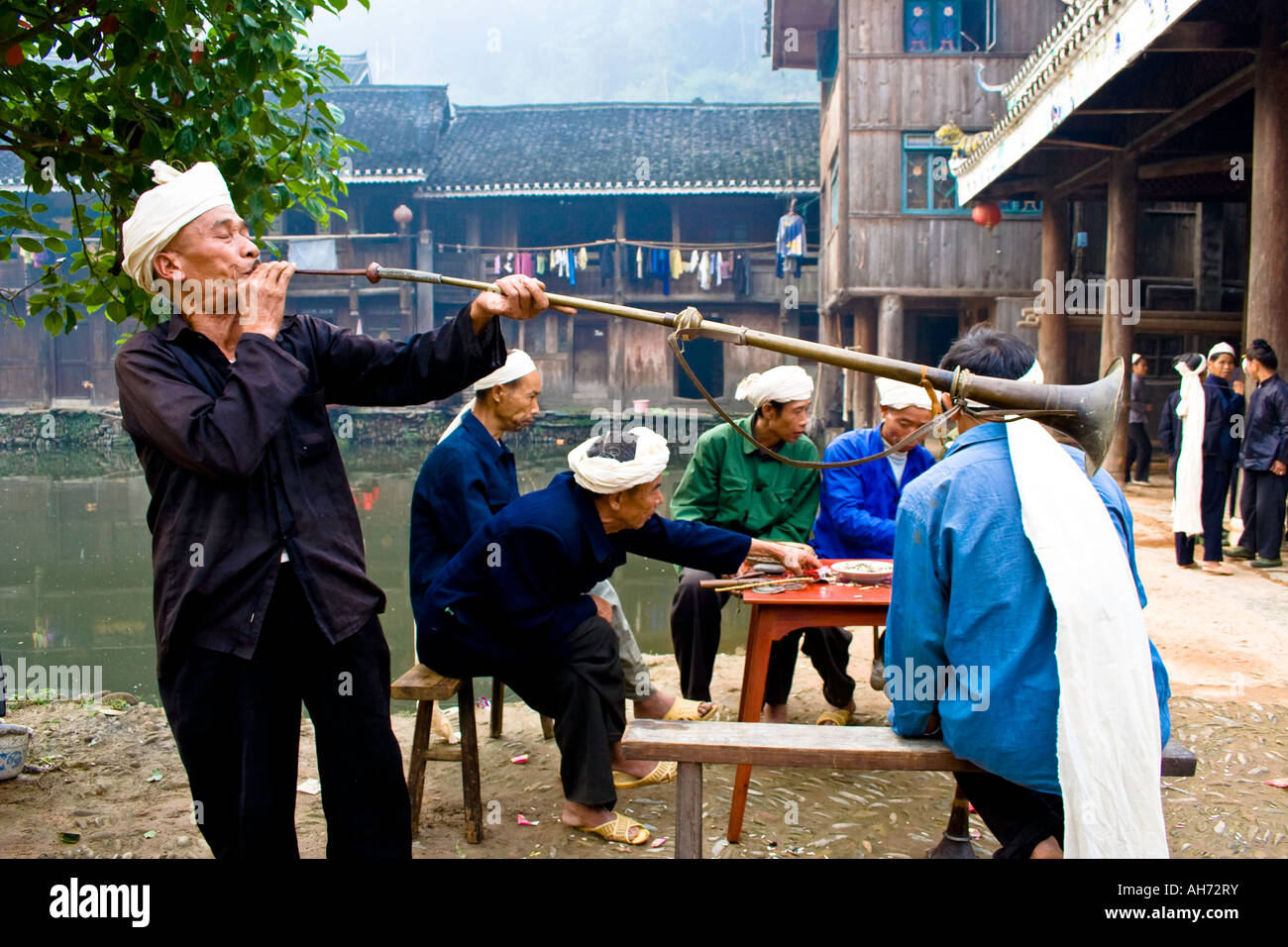 L'uomo Soffia lungo il corno di ottone per Dong cinese minoranza etnica funerale Zhaoxing Cina Foto Stock