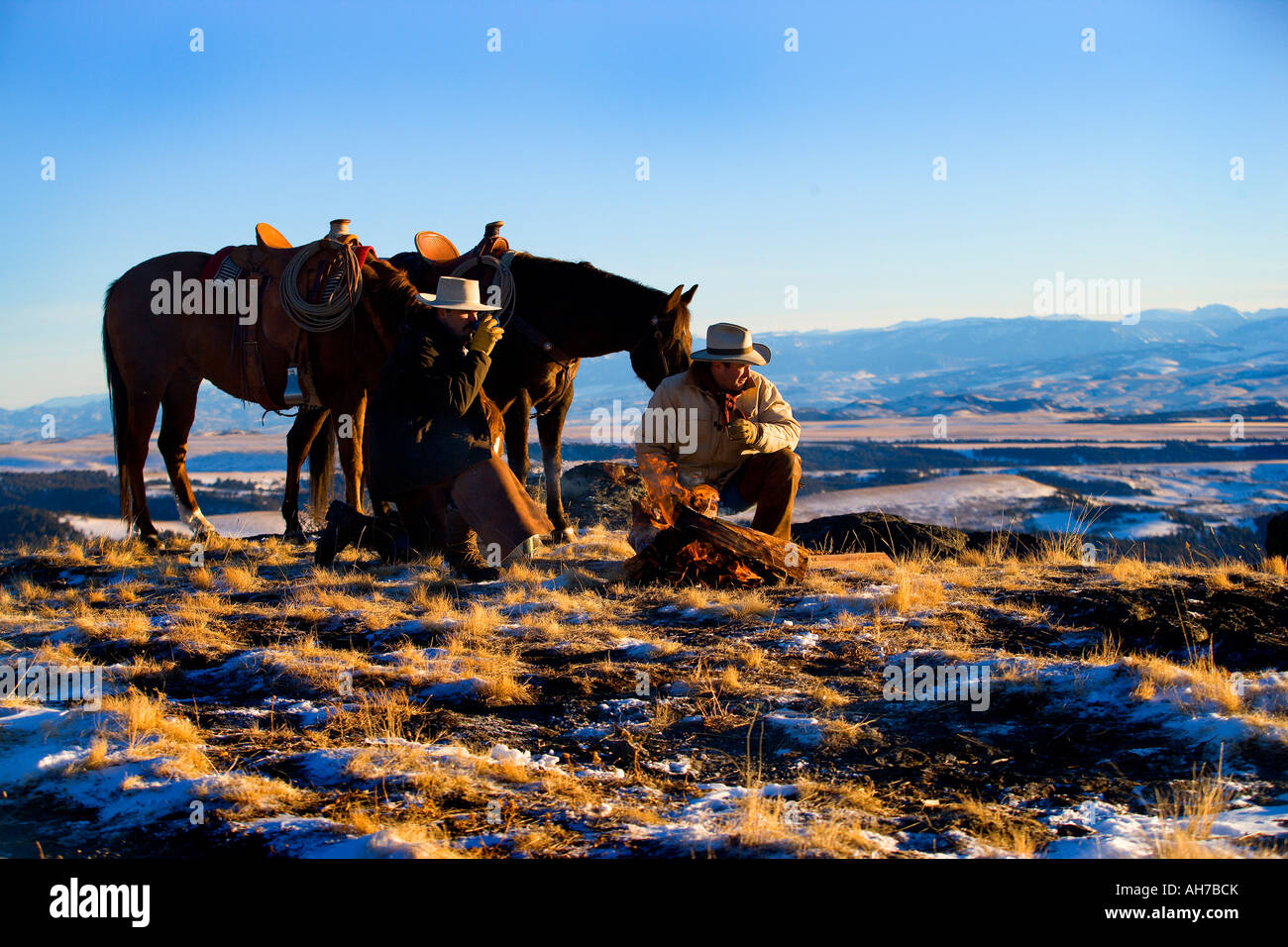 Due uomini inginocchiato a terra di fronte a un falò Foto Stock