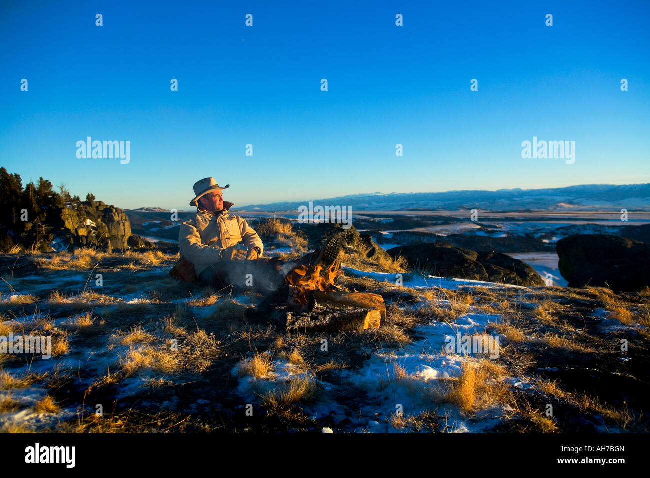 Uomo maturo seduto davanti a un falò Foto Stock