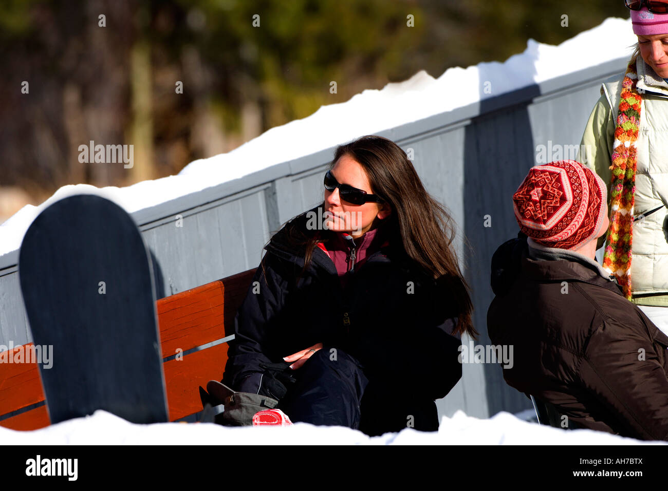 Giovane donna seduta su una panchina indossando occhiali da sole Foto Stock