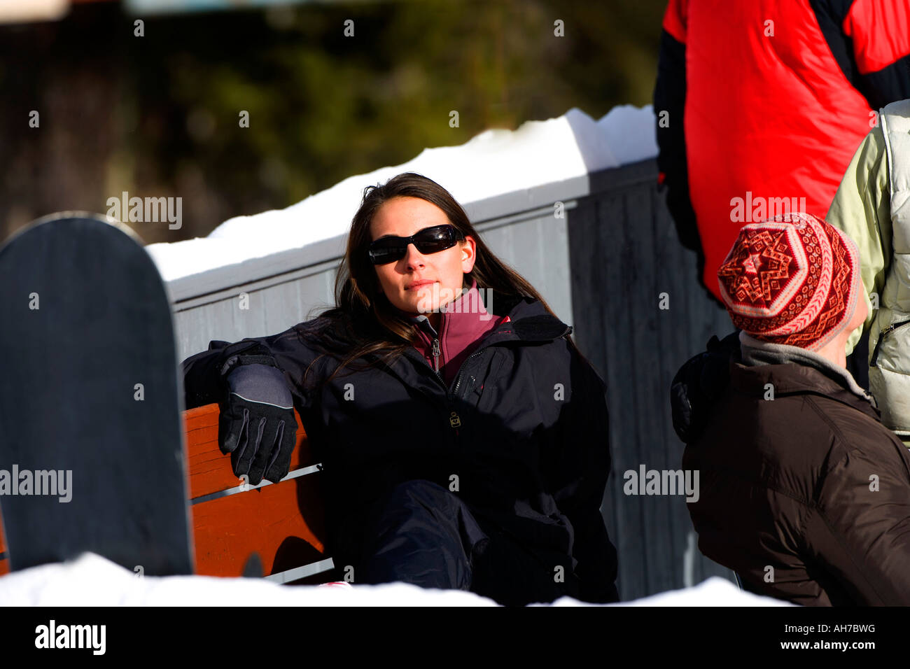 Giovane donna seduta su una panchina indossando occhiali da sole Foto Stock