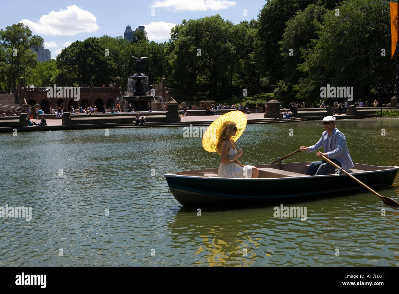Giovane uomo remare una barca con una giovane donna seduta di fronte a lui tenendo un ombrellone, Central Park, Manhattan, New York City, Ne Foto Stock