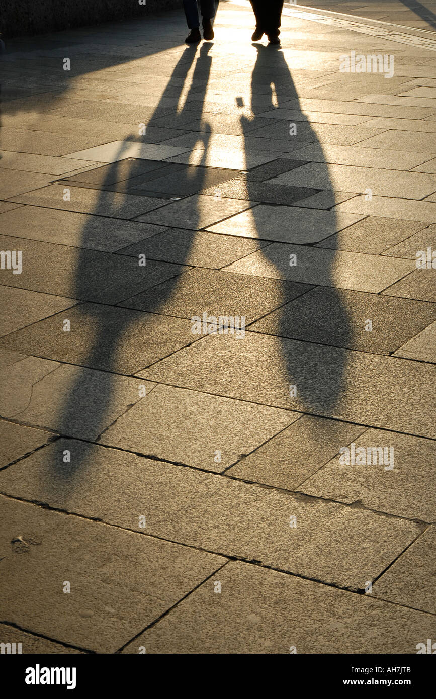 Lunghe ombre proiettate da due persone che camminano con il sole che  tramonta dietro di loro Foto stock - Alamy