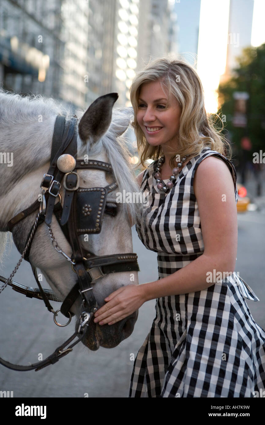 Giovane donna in piedi con un cavallo e sorridente Foto Stock