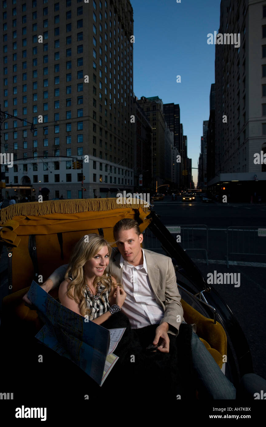 Coppia giovane di equitazione in un carrello horsedrawn e tenendo una road map, Central Park, Manhattan, New York, New York, Stati Uniti d'America Foto Stock